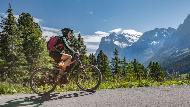 Bikerin fährt mit E-Bike durch Berge