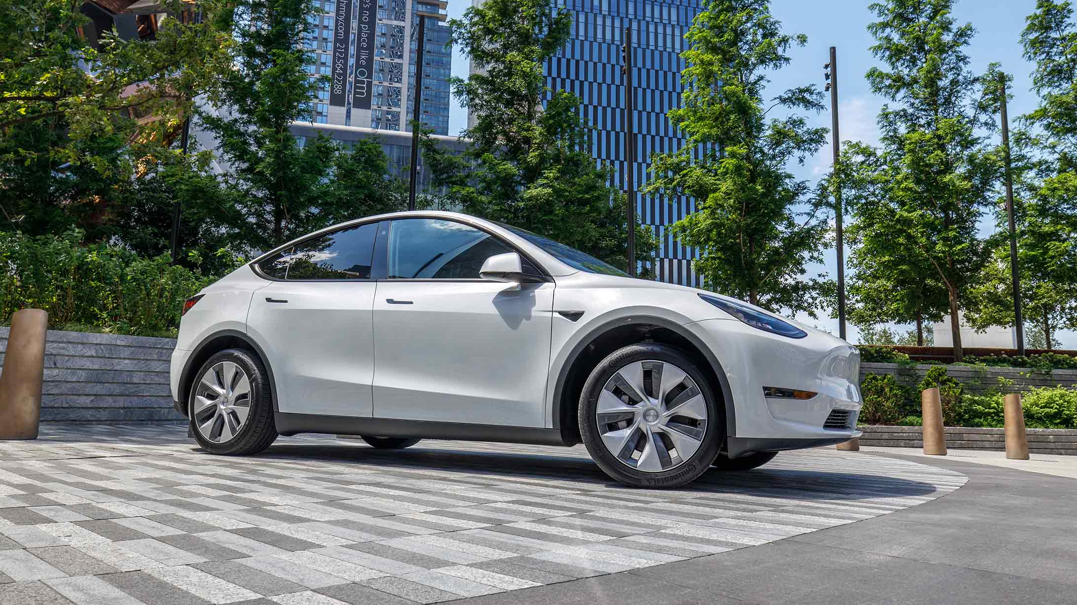 Tesla Model Y Seitenansicht, Autofarbe weiss, Auto steht draussen auf einem Parkplatz