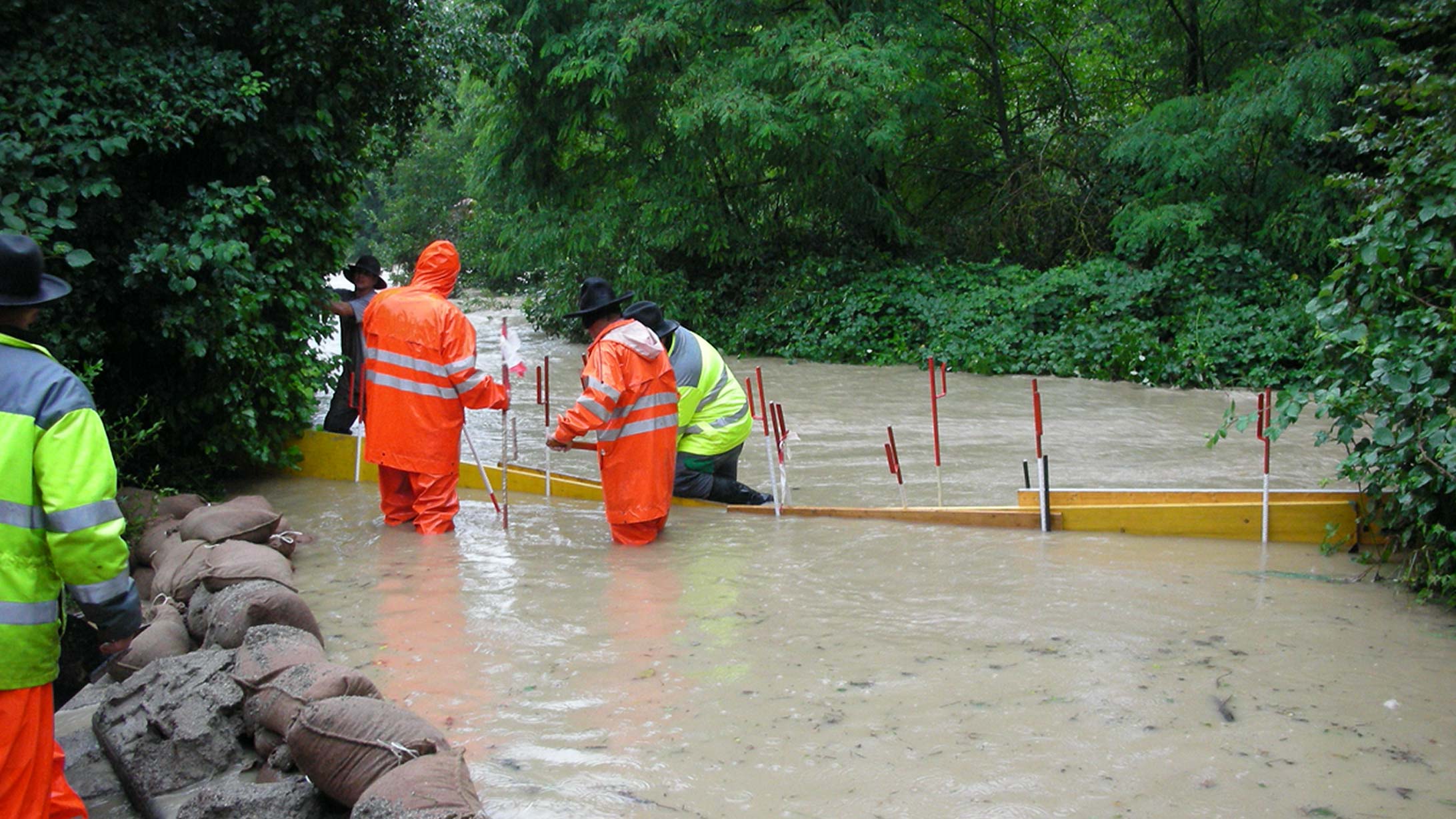 Eine gruppe Männer steht in einem überfluteten Fluss und baut eine Barriere auf