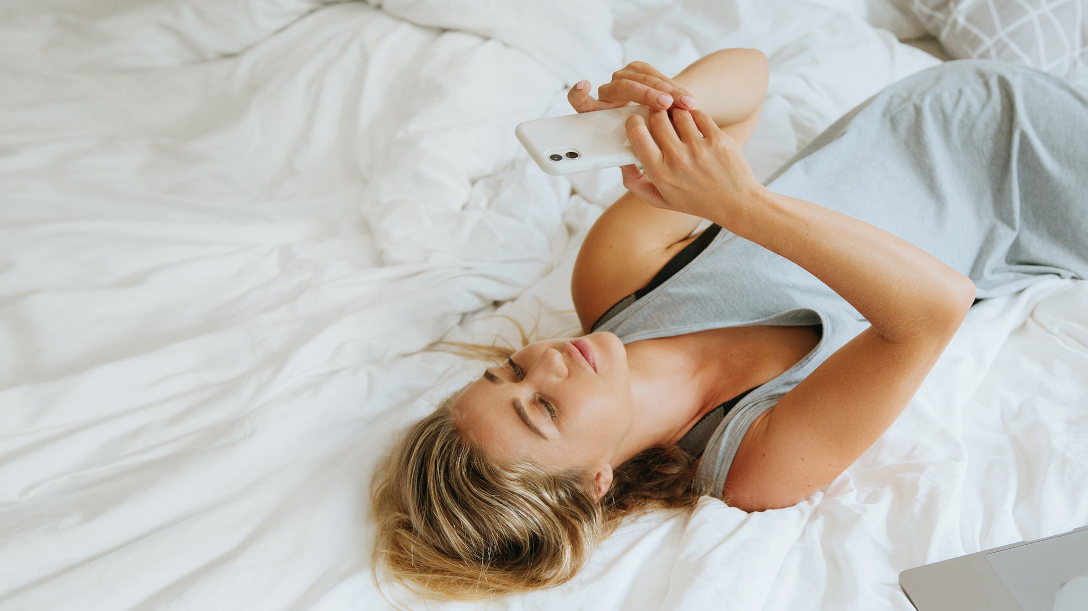 Smart Home: Eine Frau liegt im Bett mit ihrem Smartphone