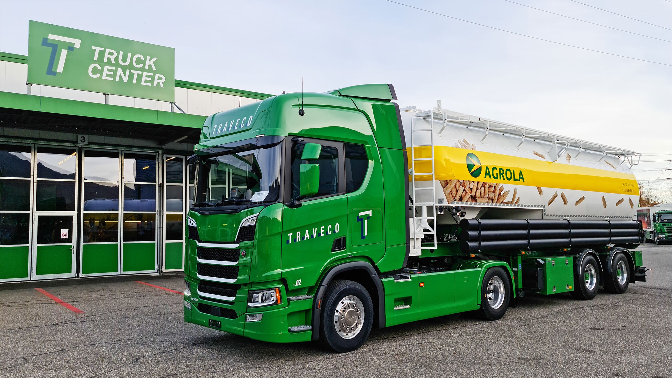 Grün-weisser Lastwagen mit Agrola-Schriftzug transportiert Holzpellets