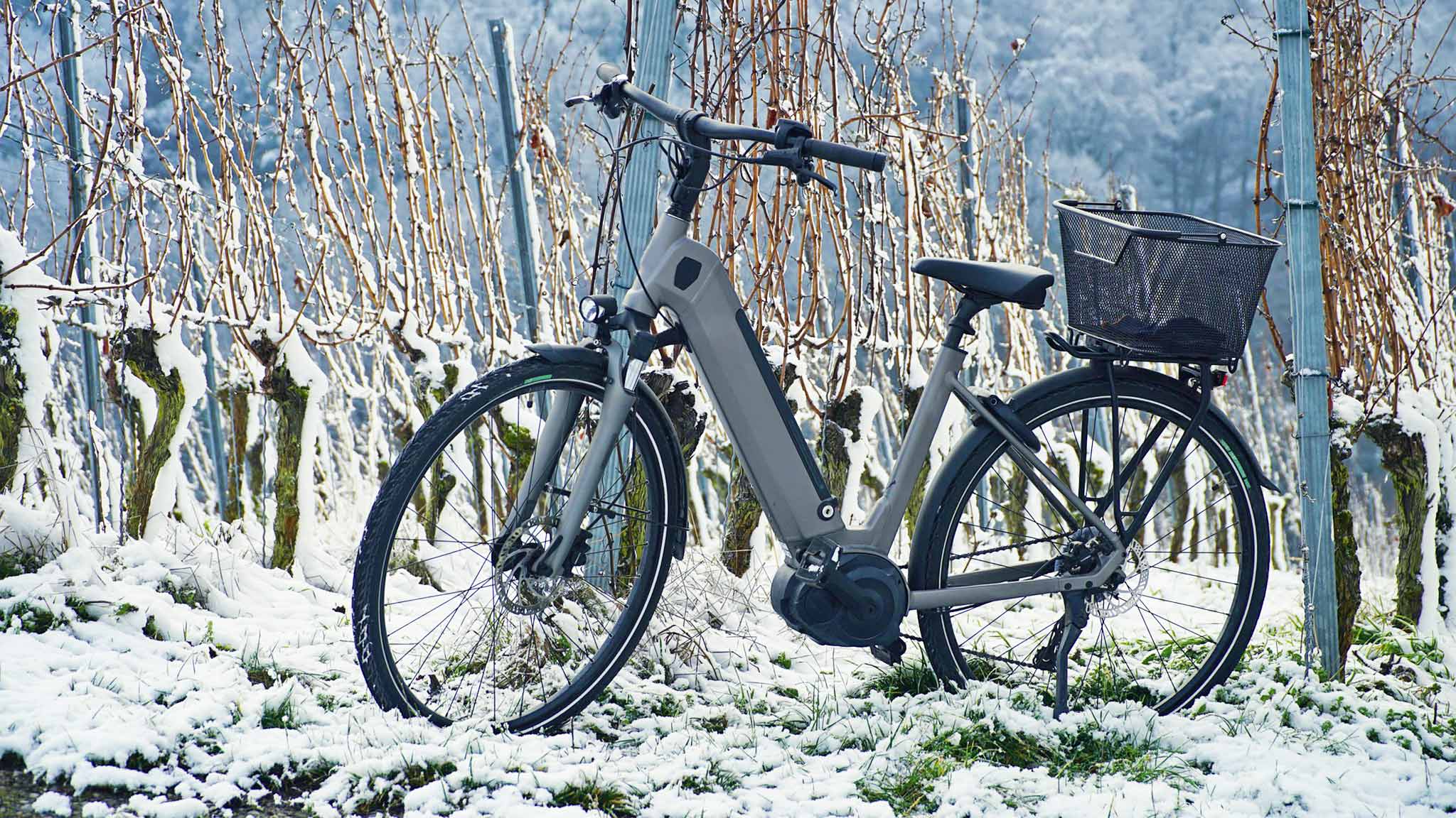 Ein E-Bike mit Korb steht im Winter im Schnee